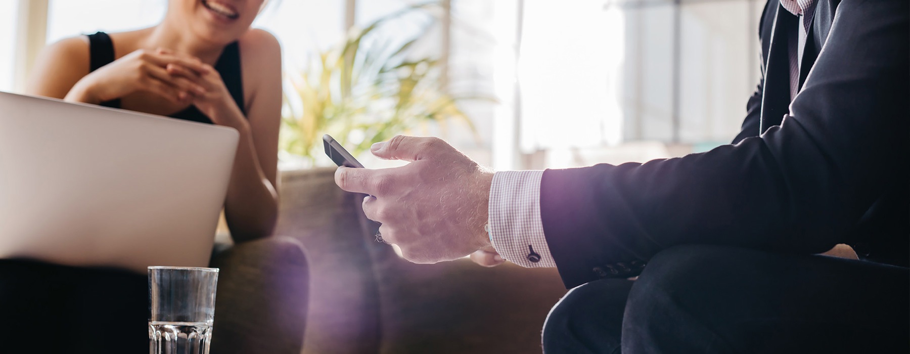 lifestyle image of a person's hand holding their device while sitting with someone in a retail environment