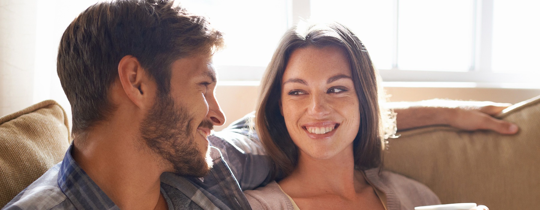 lifestyle image of a couple smiling at each other in a bright living room